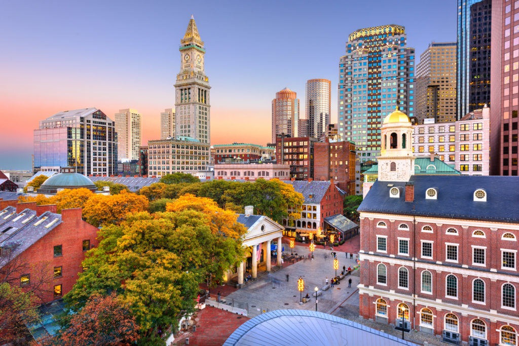 The town of Boston, Massachusetts at sunset, with a combination of skyscrapers and old university buildings. This image is featured in the Students Fare student travel blog, "Best College Towns in America," which describes the top university cities in the USA.