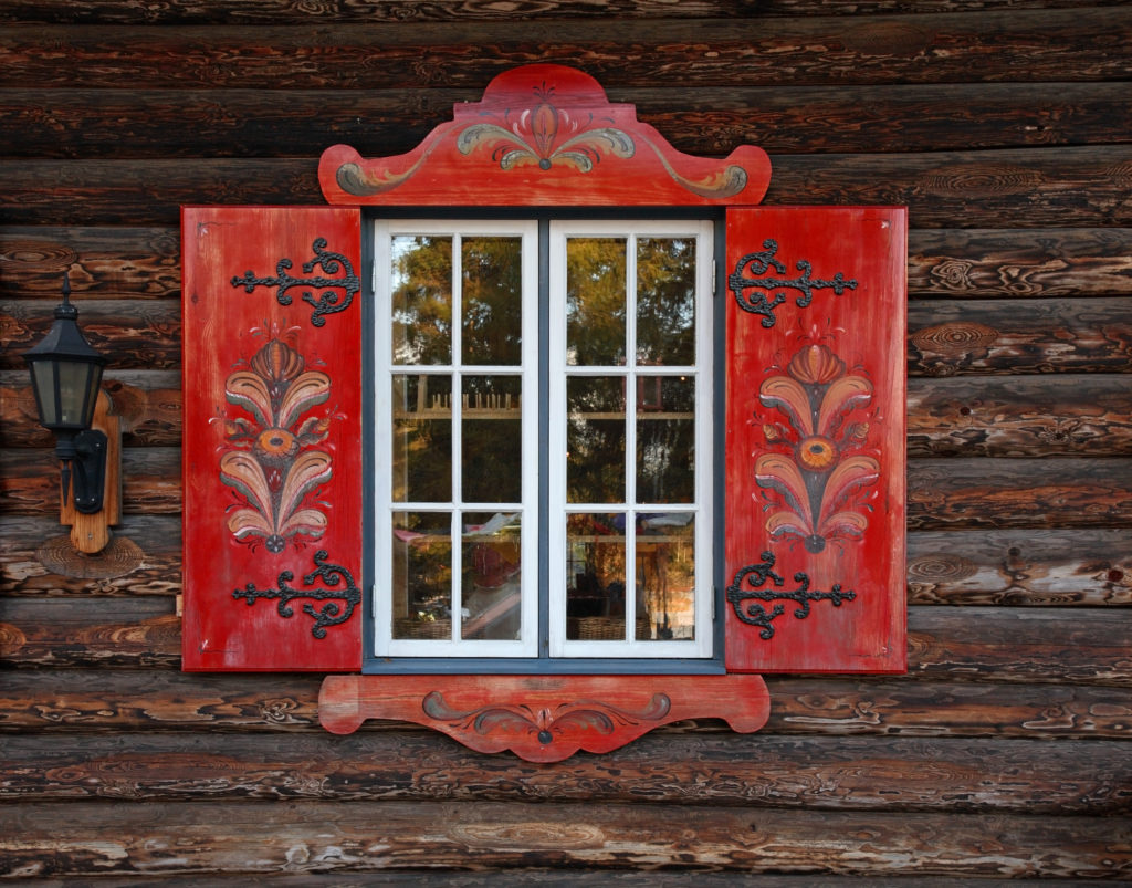 An up-close shot of the Tomteland House of Santa Clause in Sweden, where traditional red shutters compliment the dark wood logs. This image is used in the Students Fare student travel blog, "Midsummer in Sweden," which describes the traditional festival and how to celebrate it.