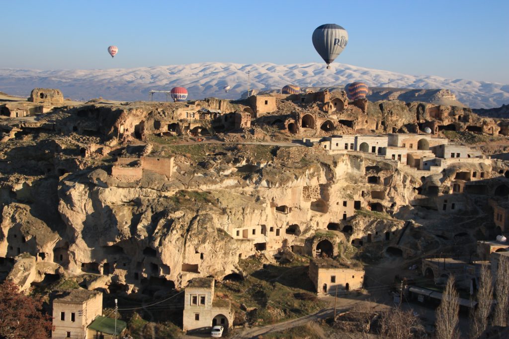 This image of Cappadocia, Turkey and hot air balloons flying by rock formations and ancient ruins is featured in the Students Fare travel blog tour guide "Best Spots for Ballooning"