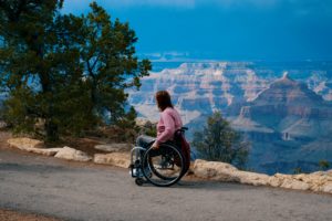 Featured in the Students Fare article, "Accessible Air Travel Guide," this image shows a female traveler using a wheelchair and viewing a gorgeous natural monument.