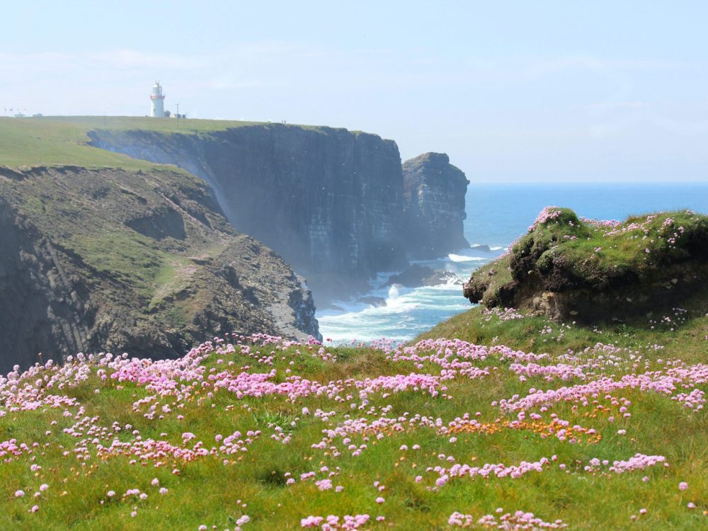 A tour of the lighthouse in the distance on a cliff with the sea below near Shannon, Ireland.