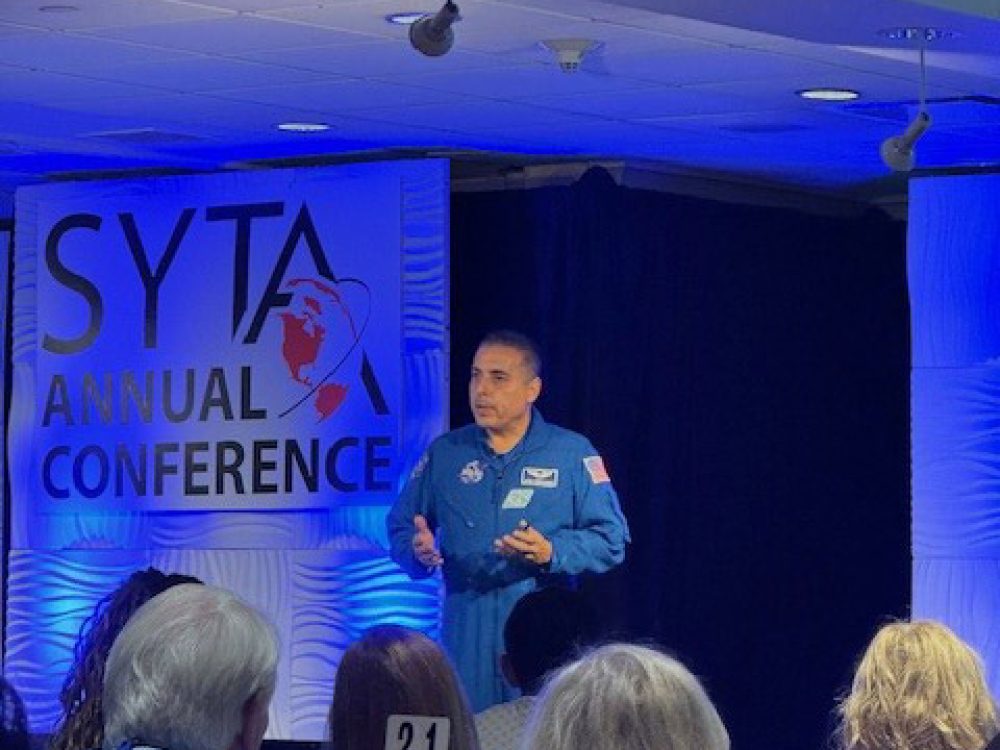 People sitting and listening to a presenter at the 2024 SYTA event for Students Fare to discuss flights, tours, hotels, and academic pursuits.
